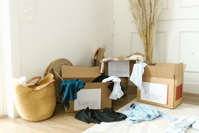 Person organizing their home by sorting things into boxes for keep, donate, and trash