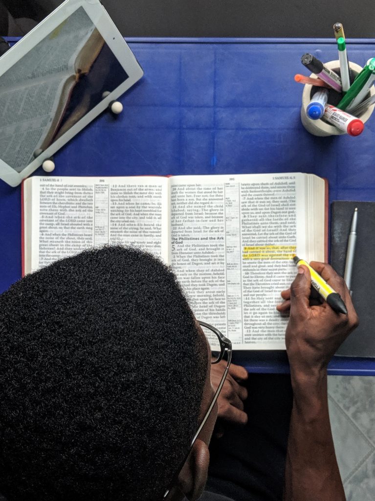 Man trying to learn how to understand the bible as he highlights a passage.