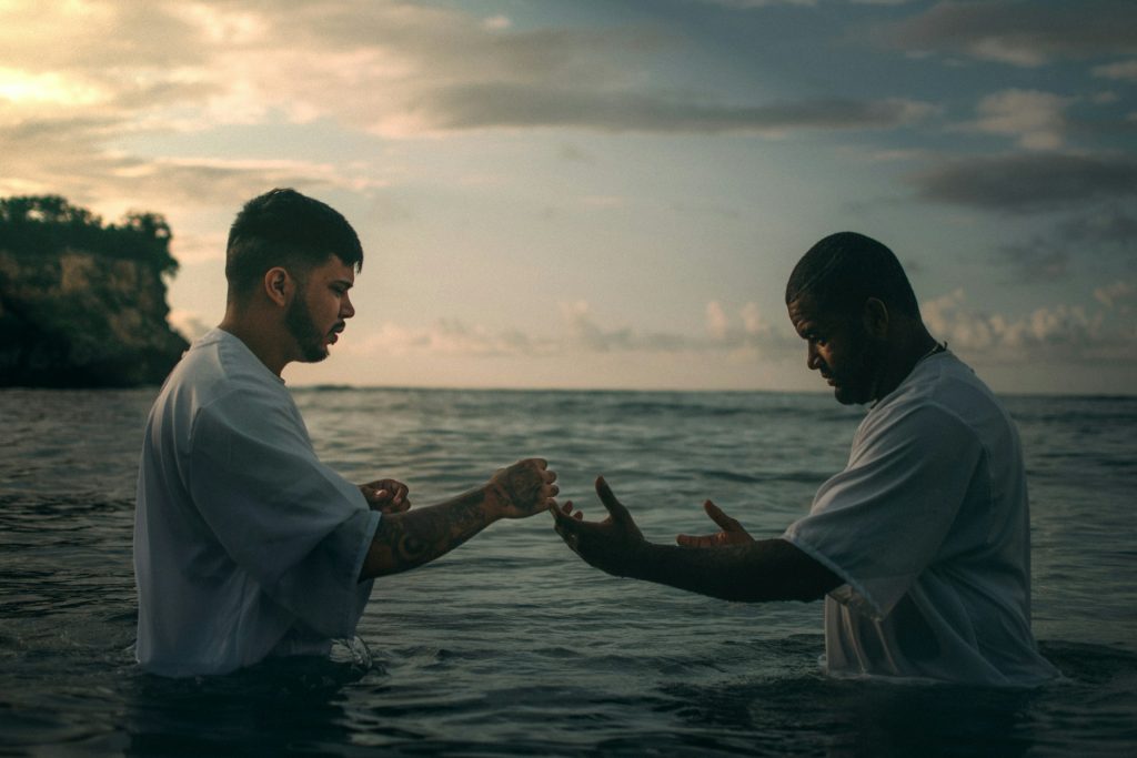 A pastor about to baptize a man in a lake.