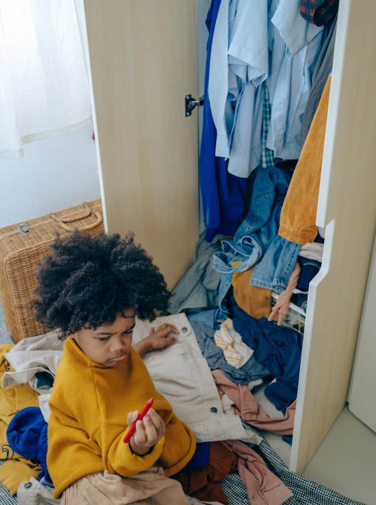 A young boy contemplates coloring on clothes and closet doors, even though he knows he isn't supposed to do it.