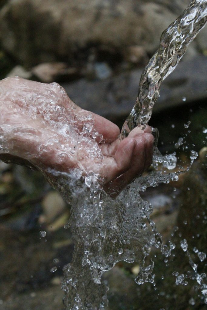 Pure water cleansing a persons hand, symbolic of how Jesus can cleanse us from sinful actions.