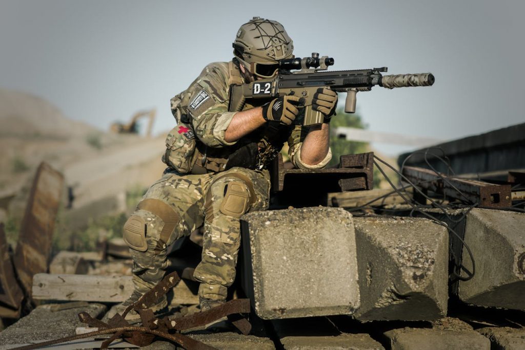 A soldier in war pointing his gun at the enemy.