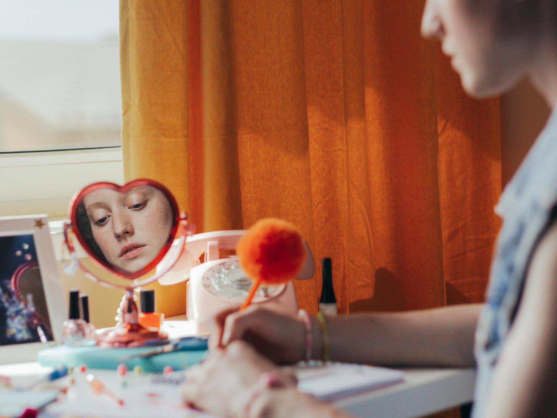 A woman's reflection in a heart shaped mirror, showing what she looks like on the outside is different than what might be inside